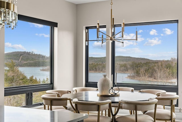 dining space featuring a healthy amount of sunlight, an inviting chandelier, and a water view
