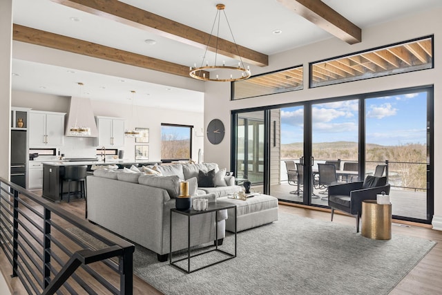 living area with recessed lighting, a notable chandelier, beam ceiling, and wood finished floors
