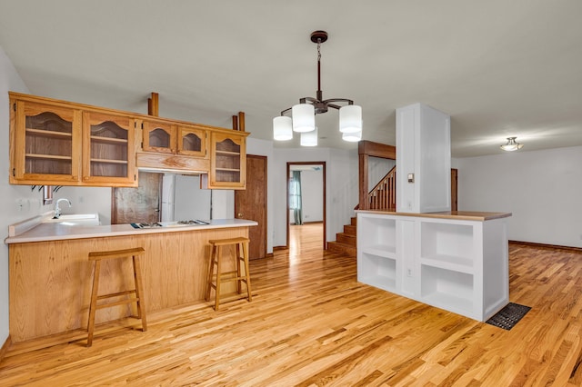 2505 Courtney Pl, West Plains, MO 65775 - kitchen with open shelves, a sink, a chandelier, light wood-type flooring, and a kitchen bar