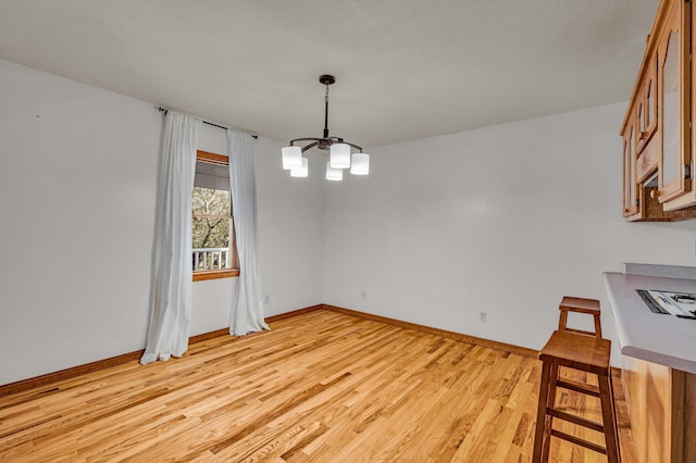 2505 Courtney Pl, West Plains, MO 65775 - unfurnished dining area with a chandelier, light wood finished floors, and baseboards