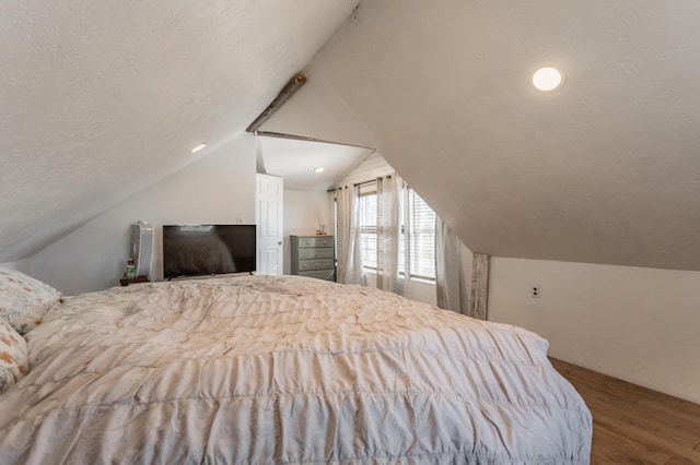 bedroom featuring lofted ceiling, a textured ceiling, and wood finished floors