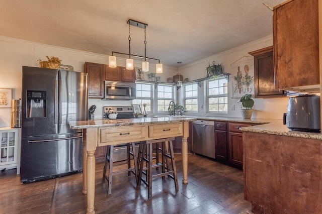 kitchen featuring ornamental molding, appliances with stainless steel finishes, a sink, light stone counters, and dark wood-style floors