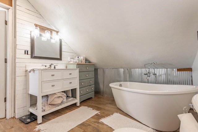 full bath featuring a soaking tub, vanity, lofted ceiling, and wood finished floors