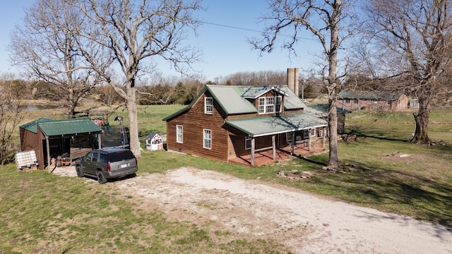 view of property exterior with driveway, a chimney, metal roof, a porch, and a yard