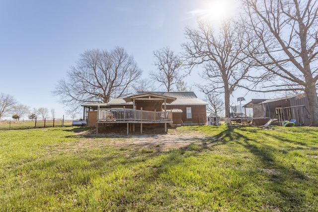 rear view of property featuring metal roof, fence, a wooden deck, and a yard