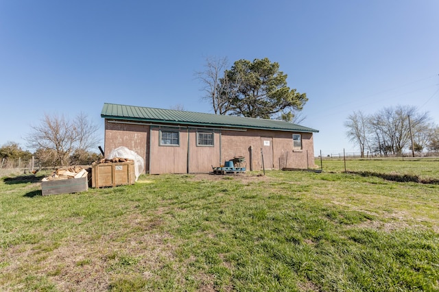 back of house with metal roof, fence, and a yard