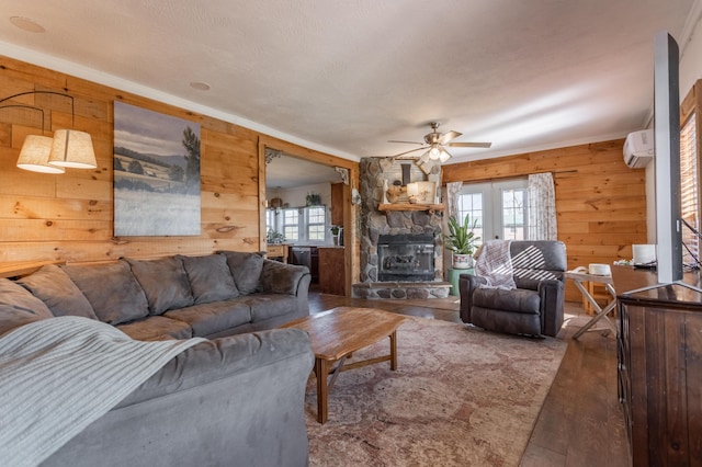 living area featuring a fireplace, a ceiling fan, wood finished floors, and a healthy amount of sunlight