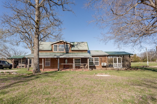rear view of property with a sunroom, metal roof, and a lawn