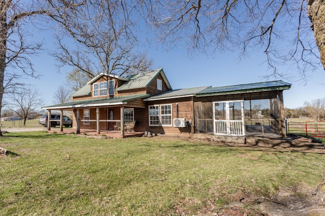 rear view of house featuring a sunroom, metal roof, fence, and a lawn