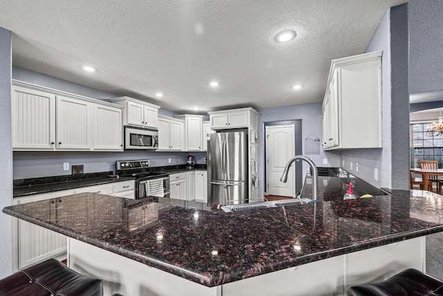445 E Sequoia St, Republic, MO 65738 - kitchen featuring appliances with stainless steel finishes, a peninsula, a sink, white cabinetry, and a breakfast bar