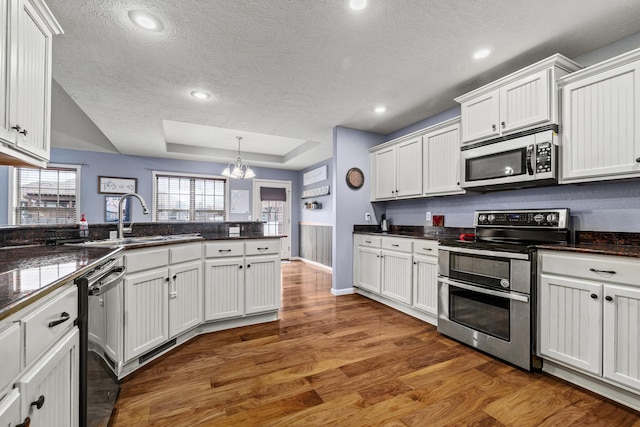 445 E Sequoia St, Republic, MO 65738 - kitchen with appliances with stainless steel finishes, a textured ceiling, a chandelier, wood finished floors, and white cabinets