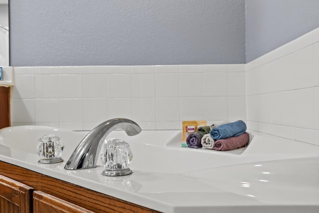 445 E Sequoia St, Republic, MO 65738 - bathroom view of tasteful backsplash, vanity, a textured wall, and a tub
