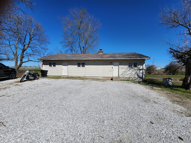rear view of property with driveway and a chimney