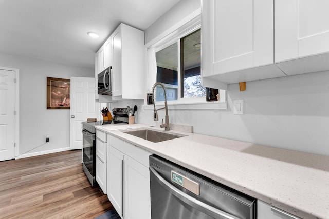 504 Brown St, Branson, MO 65616 - kitchen with appliances with stainless steel finishes, a sink, white cabinetry, light wood-style floors, and baseboards