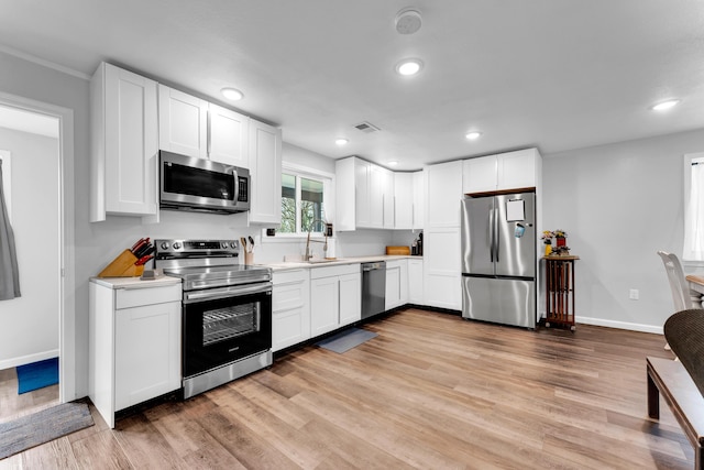 504 Brown St, Branson, MO 65616 - kitchen with stainless steel appliances, light countertops, light wood-style flooring, white cabinetry, and recessed lighting