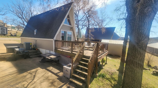 back of property featuring a shingled roof, central air condition unit, a wooden deck, and a patio area
