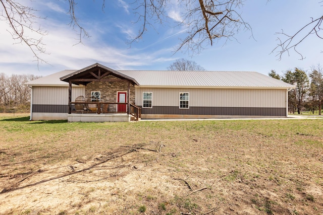 view of front facade featuring a front lawn, metal roof, and stone siding