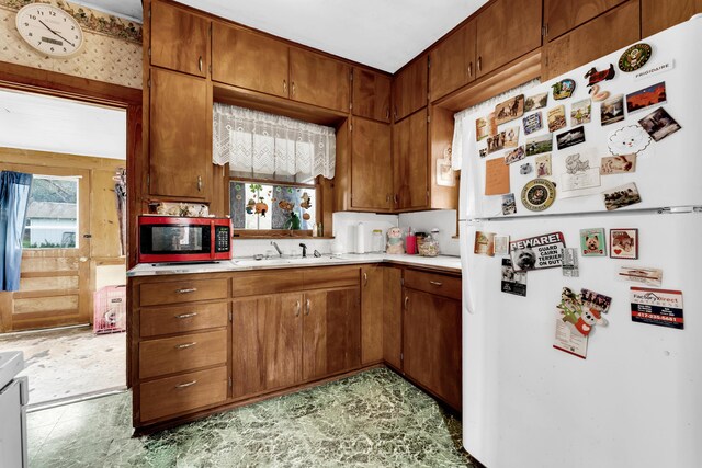 kitchen featuring light countertops, a sink, a healthy amount of sunlight, and freestanding refrigerator