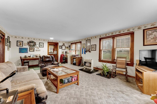 living area with baseboards, heating unit, and light colored carpet