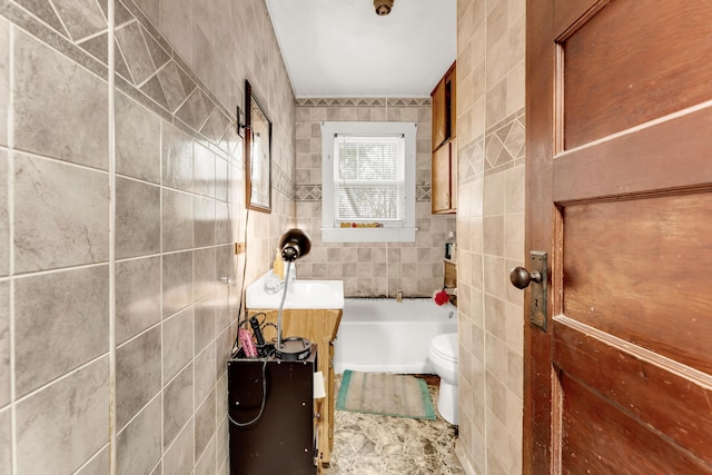 full bathroom with a tub, toilet, vanity, and tile walls