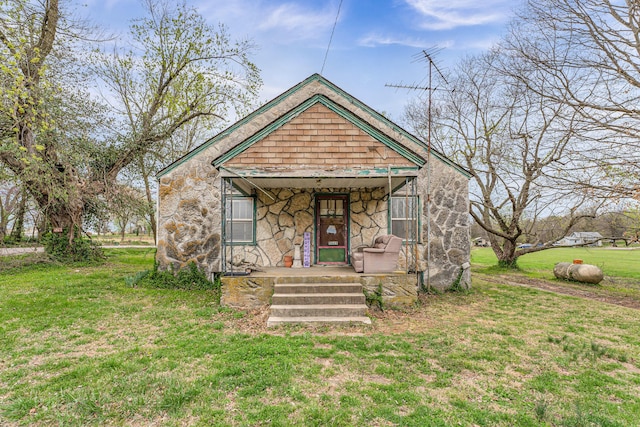 bungalow-style home featuring stone siding and a front lawn