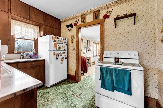 kitchen with light countertops, wallpapered walls, and white appliances