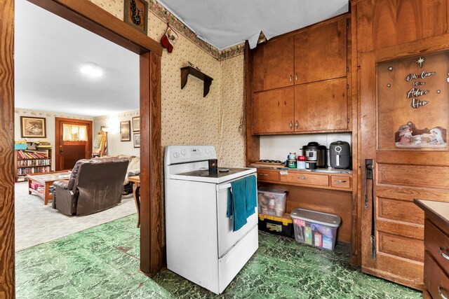 kitchen with tile patterned floors, light countertops, brown cabinets, wallpapered walls, and electric range