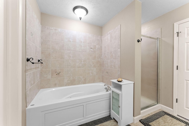 full bathroom with a stall shower, tile patterned flooring, a bath, and a textured ceiling