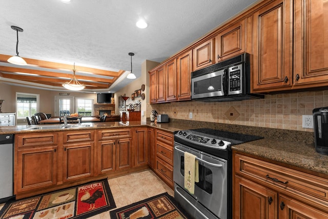 kitchen with brown cabinetry, stainless steel appliances, a sink, open floor plan, and backsplash
