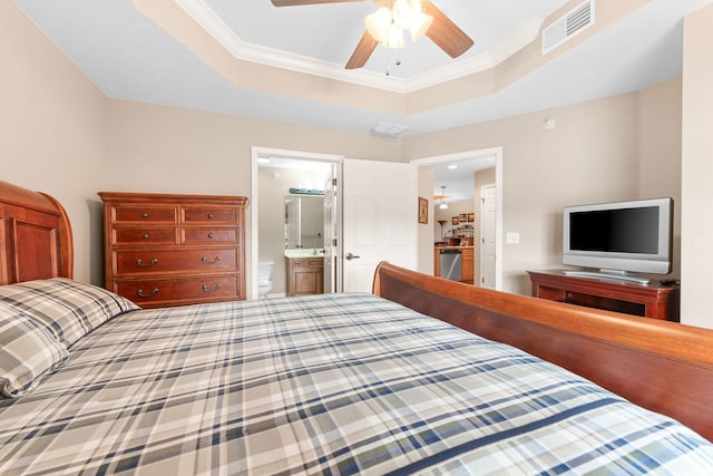 bedroom featuring ornamental molding, a tray ceiling, ensuite bath, and visible vents