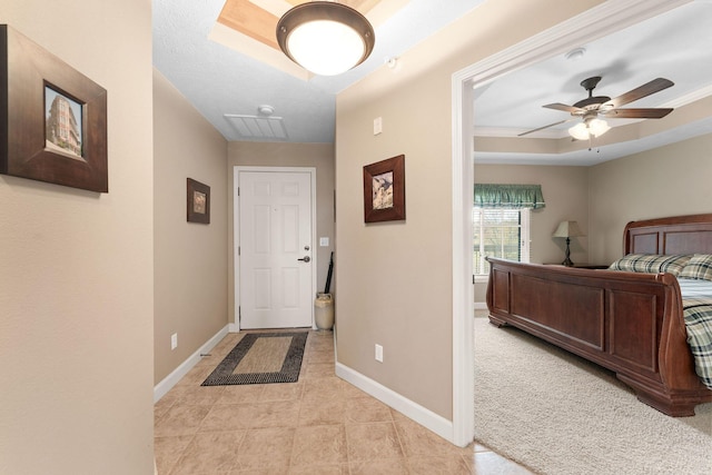 interior space with a tray ceiling, baseboards, light tile patterned flooring, visible vents, and a ceiling fan
