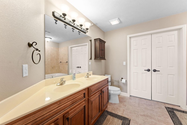 full bath featuring double vanity, a sink, tile patterned floors, and toilet