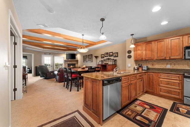 kitchen featuring a raised ceiling, a sink, dishwasher, black microwave, and brown cabinets