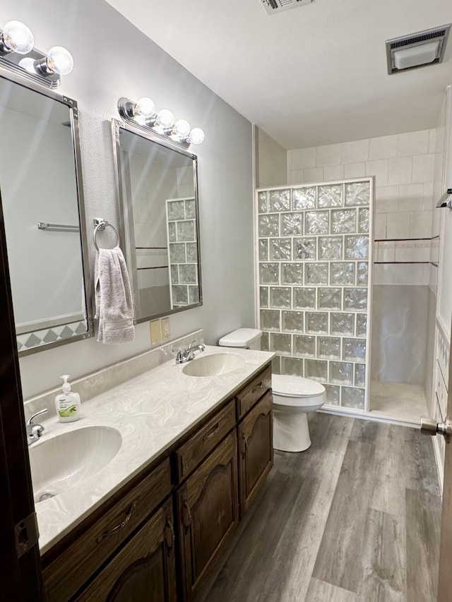 full bath featuring visible vents, a sink, a walk in shower, and wood finished floors