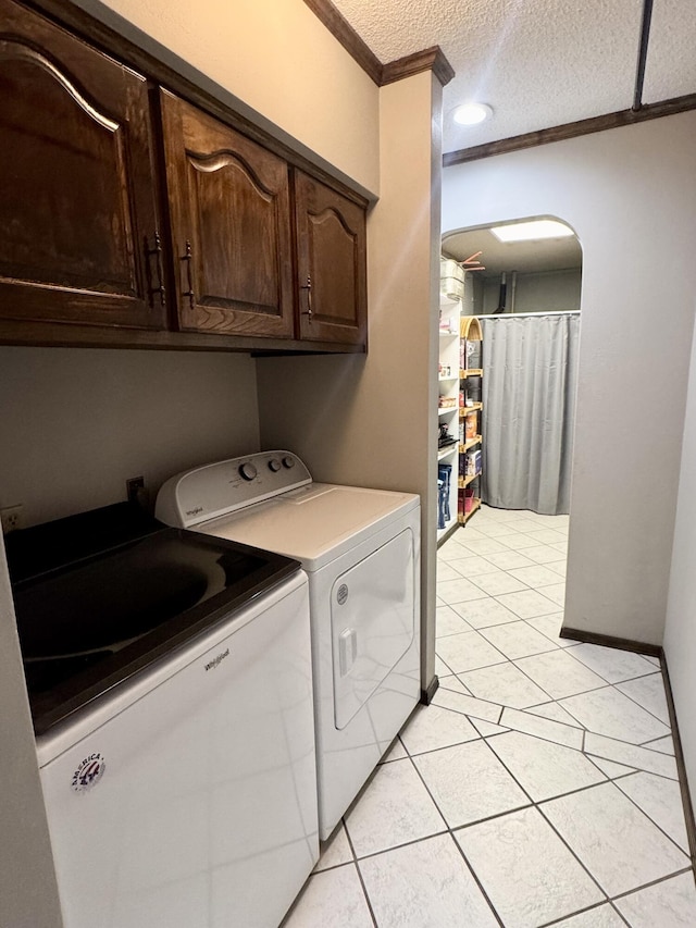 clothes washing area featuring light tile patterned floors, a textured ceiling, washer and clothes dryer, and ornamental molding