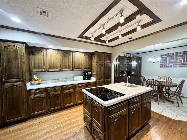 kitchen with black electric cooktop, light countertops, light wood-type flooring, a textured ceiling, and visible vents