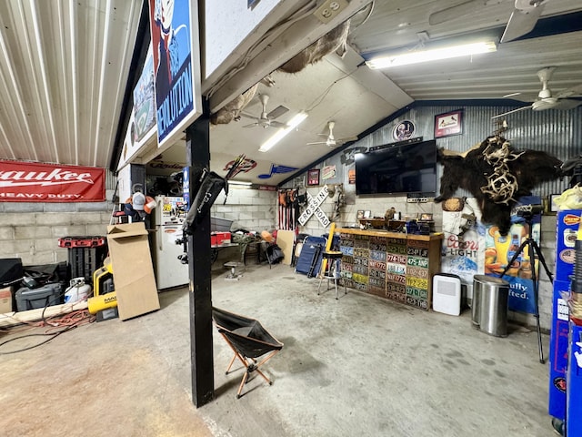 garage featuring concrete block wall, a ceiling fan, and a workshop area