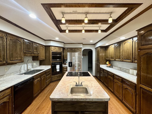 kitchen with a center island, a sink, arched walkways, light wood finished floors, and black appliances