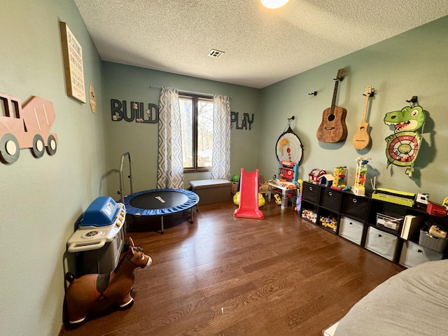 recreation room with visible vents, wood finished floors, and a textured ceiling