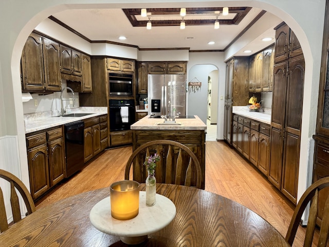 kitchen with light countertops, dark brown cabinets, a sink, light wood-style floors, and black appliances