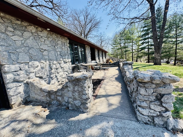 view of home's exterior featuring stone siding and a patio