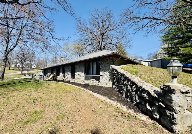 view of property exterior with stone siding, a yard, and a chimney