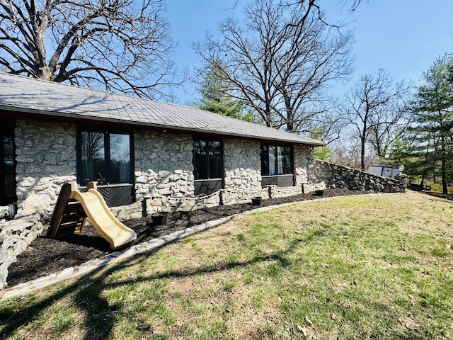 view of side of home featuring stone siding and a yard