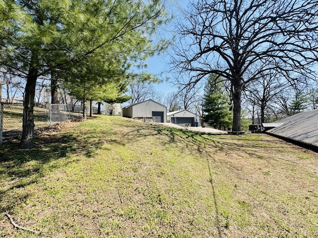 view of yard with an outbuilding, fence, a detached garage, and a pole building