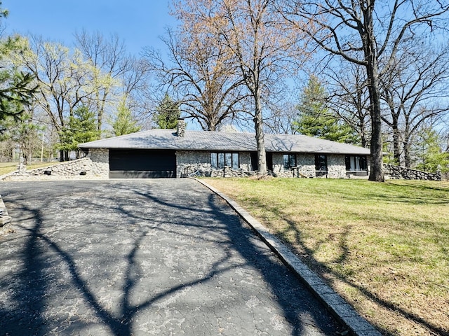 view of front of home with a front lawn, driveway, a garage, and a chimney