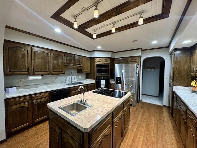 kitchen with arched walkways, black appliances, a sink, and light wood-style floors