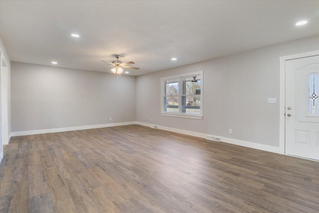spare room with baseboards, visible vents, wood finished floors, and a ceiling fan