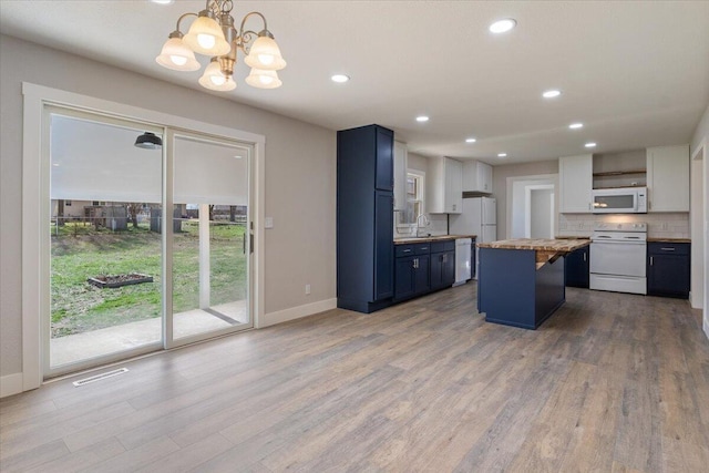 kitchen with wood finished floors, visible vents, a chandelier, and white appliances
