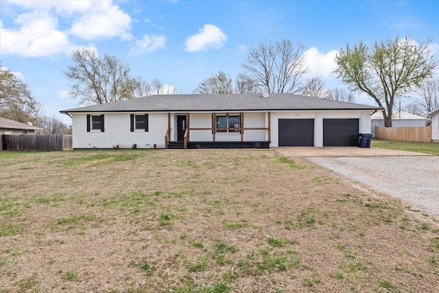 ranch-style home with driveway, an attached garage, fence, and a front lawn