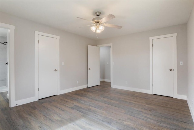 unfurnished bedroom featuring baseboards, wood finished floors, and ensuite bath